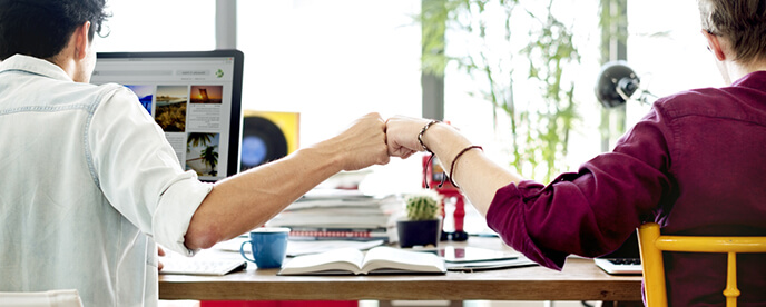 coworkers sitting side by side fist bump