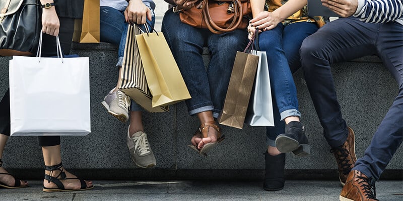 shoppers sitting on a ledge holding purchases