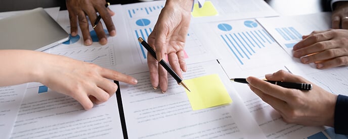 coworkers gather over business documents scattered on a table