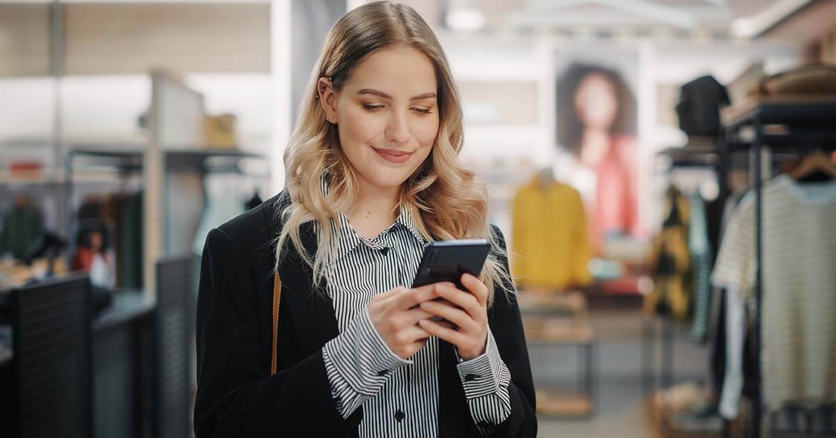 woman holding phone while shopping in a retail store