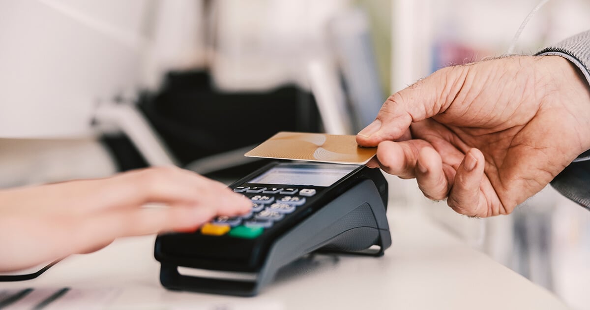 person holds credit card up to payment terminal for contactless payment