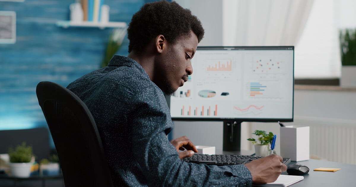 project manager working at a computer screen with graphs and charts on it