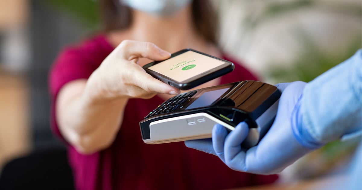 woman wearing a mask pays using contactless payment