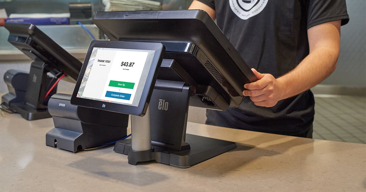 qsr employee stands at point of sale system