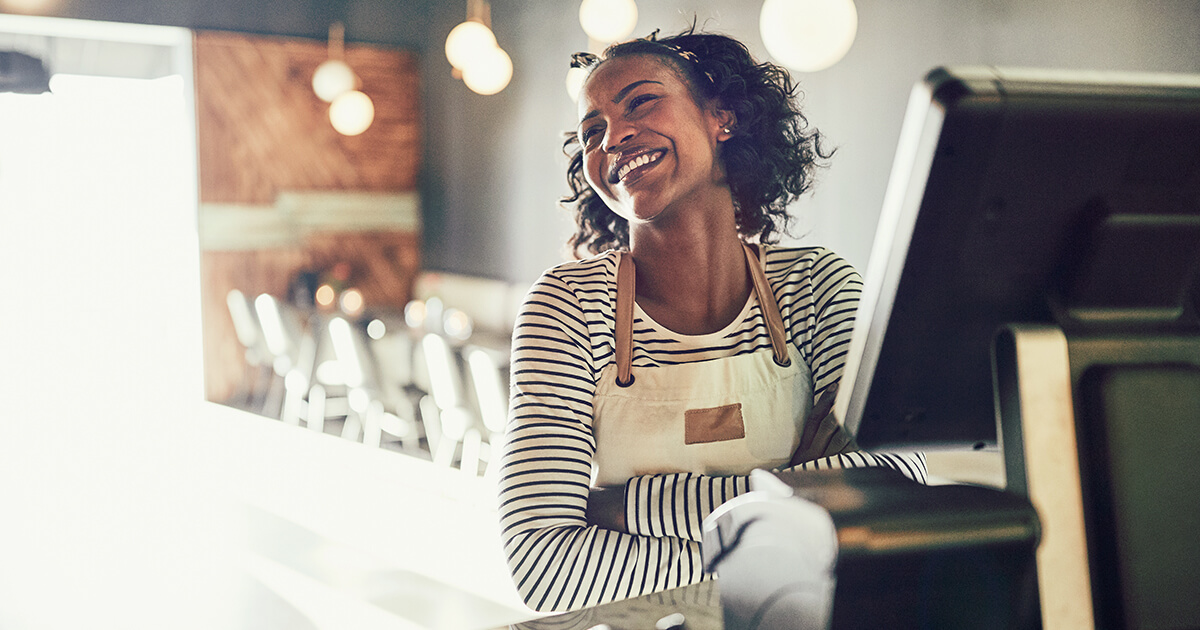 restaurant employee smiles behind point of sale system