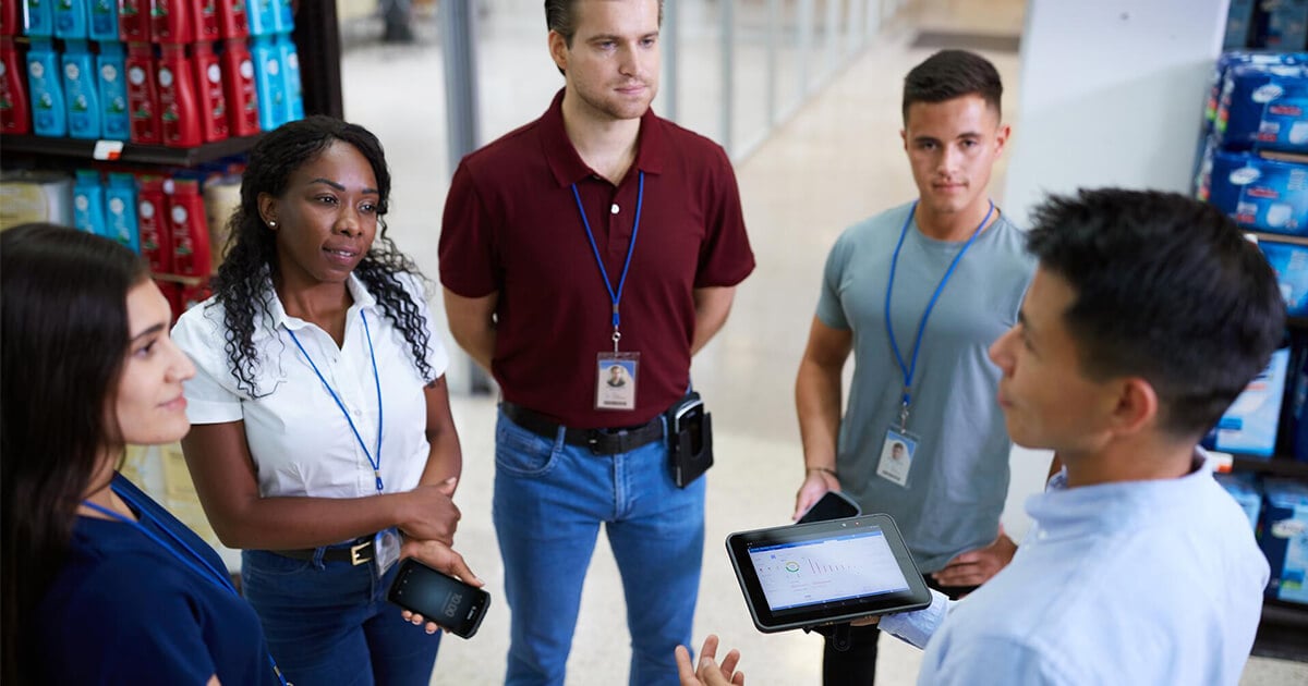 retail employees stand in a group holding mobile devices