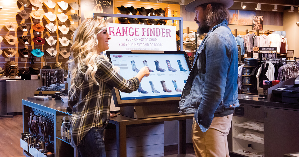 woman helps customer at in-store digital kiosk