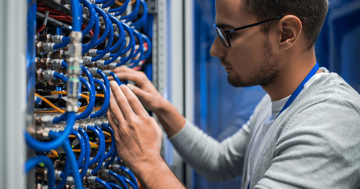 man adjusts wires in a network cabinet