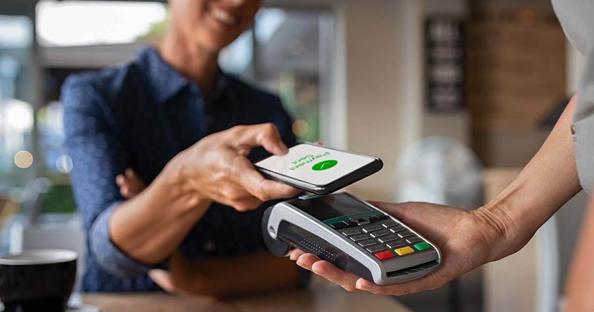 woman at point of sale holding payment terminal to customer 