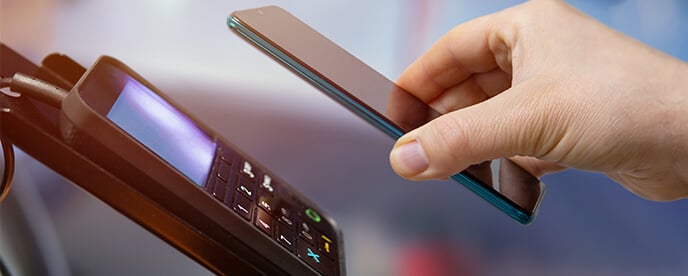 customer using phone for contactless payment at payment terminal