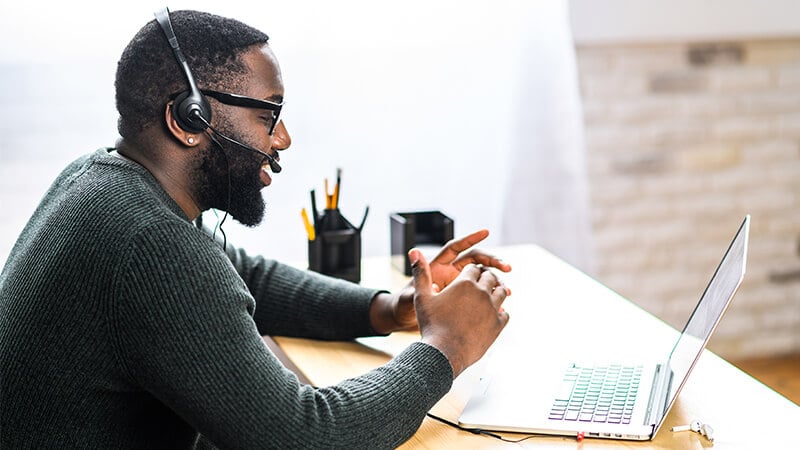 man sitting at desk working at computer wearing headset