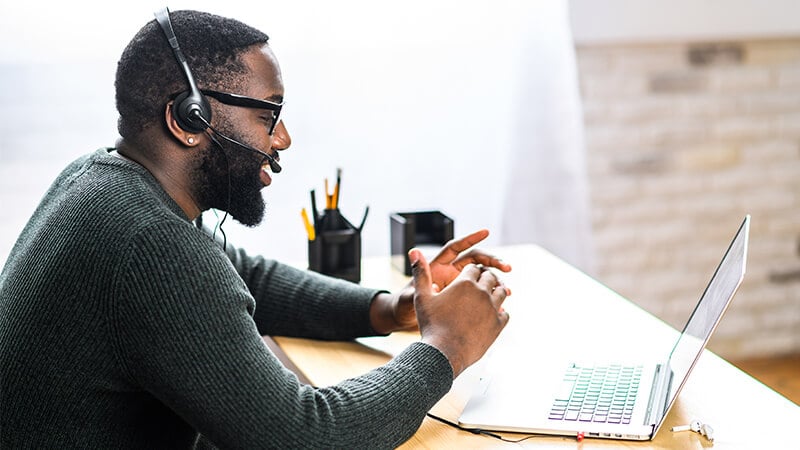 man working at laptop wearing phone headset