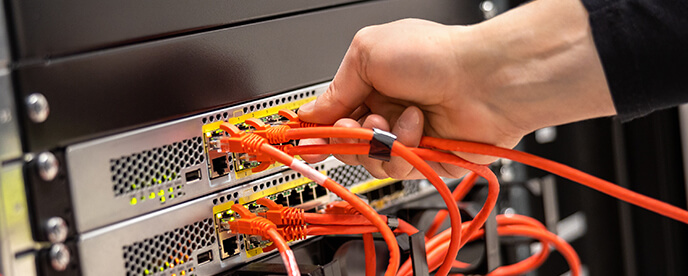 technician plugging in cables in a network cabinet