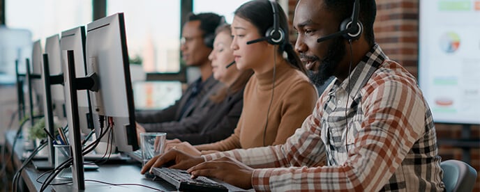 help desk team sits at computers wearing headsets