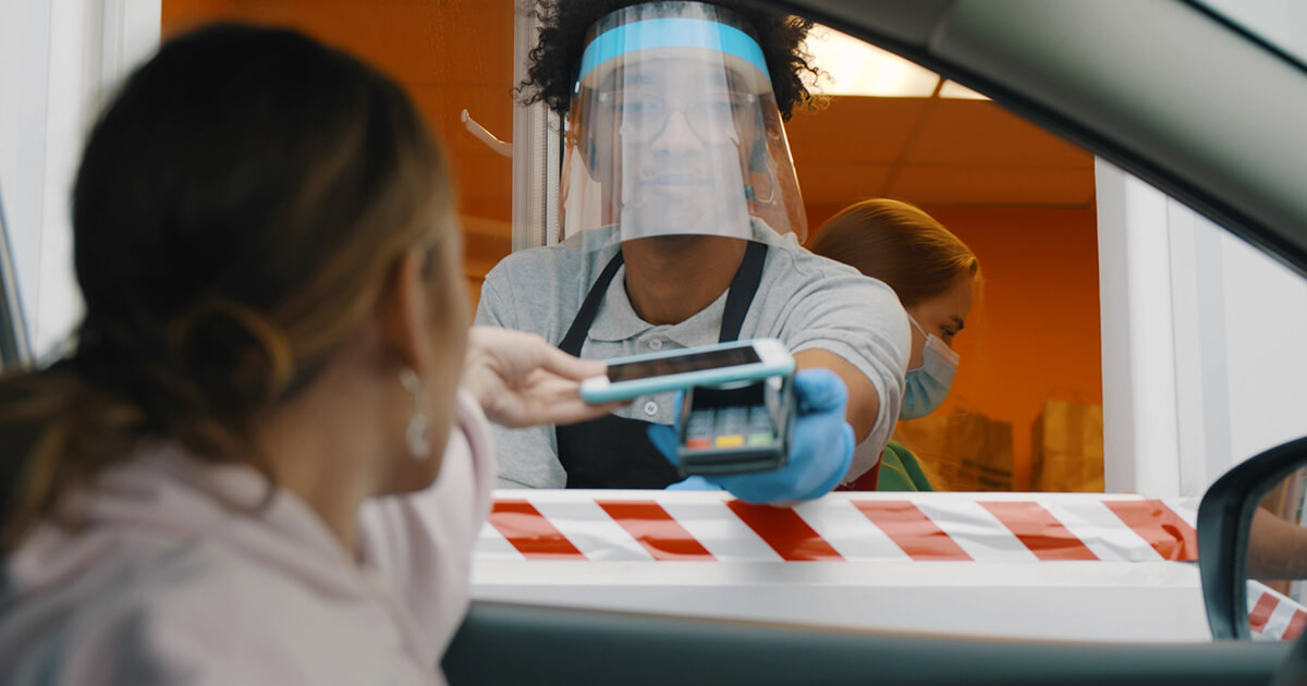 restaurant drive-thru employee wearing face shield accepts contactless payment