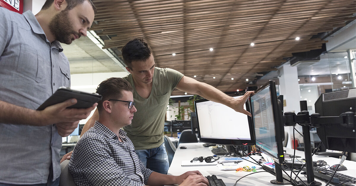 three men gathered around a computer