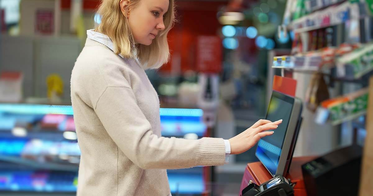 woman using self-service kiosk in store